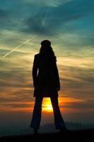 Girl standing with sun between legs photo