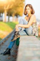 Young beautiful girl sitting on a low wall in a park in the city photo