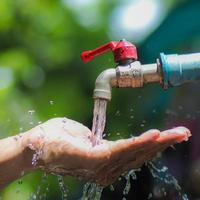 Water concept in everyday life. Hands supporting the water flowing from the faucet. water splashing from the tap photo