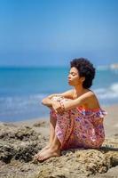 Calm black woman resting against sea photo