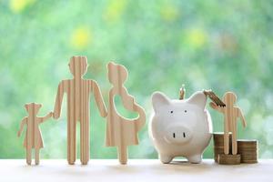 Model family with piggy bank and stack of coins money on natural green background,Save money for prepare in future and family finance concept photo