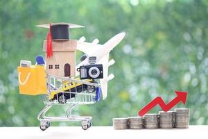 concepto de crisis financiera inflacionaria, casa modelo o propiedad en modelo de carrito de compras en miniatura y gráfico de flecha roja sobre fondo verde natural foto