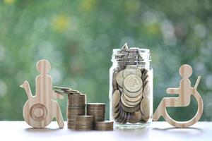 hombre en silla de ruedas y moneda de oro en la botella de vidrio sobre fondo verde natural, ahorre dinero para prepararse en el futuro y el concepto de persona discapacitada foto