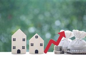 Finance, Model house with red arrow graph and money bag on natural green background,Business investment and Save money for prepare in future concept,Inflation photo
