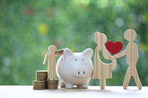 Model family with piggy bank and stack of coins money on natural green background,Save money for prepare in future and family finance concept photo