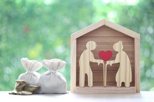 Mutual fund,Love couple senior with model house and coins money in the bag on natural green background, Save money for prepare in future and pension retirement concept photo