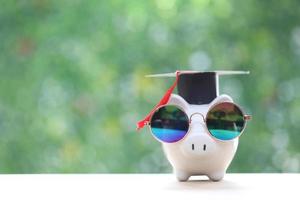 Saving money for education concept, Graduation hat on piggy on nature green background photo