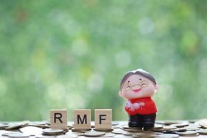 RMF - Retirement Mutual Fund, Senior woman with RMF word on stack of coins money on natural green background, Save money for prepare in future and pension retirement concept photo