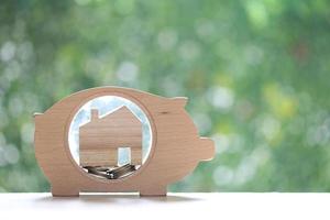 Stack of coins money in piggy bank wood and Model house on natural green background, Business investment and Real estate concept photo