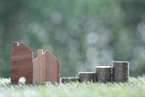 Mortgage,Model house and stack of coins money on natural green background,Business investment and real estate concept photo