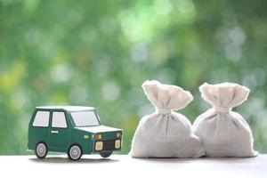 Finance, Model car and money bag on natural green background,Business investment and save money for prepare in future concept photo