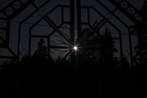Sun shines through fence. Dark fence. photo
