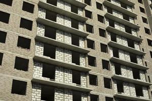 Empty windows in building. Unfinished house in city. Construction on street. photo