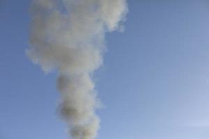 humo y cielo. el humo negro se eleva en el aire. foto