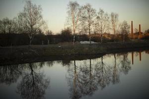 View of lake. Reflection in water. Details of outskirts of city. photo