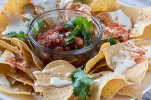 nachos mexicanos con salsa y crema agria en chips de maíz foto