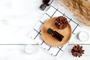 Autumn skin care concept. Bottle of pine essential oil on a white wooden background. Aromatherapy and eco-friendly cosmetics. photo