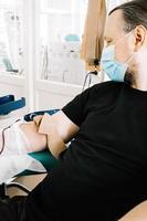 Middle-aged man donates blood in medical laboratory. International Blood Donation Day. photo