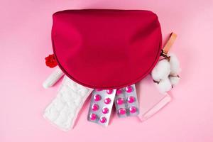 bolsa cosmética rosa y productos de higiene femenina para la menstruación. toallas higiénicas, tampones, tabletas. foto