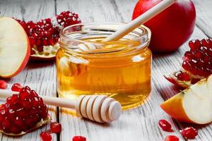 Jar with honey, apples and pomegranates on white wooden background. Happy Rosh Hashanah. Traditional symbols of Jewish New Year celebration. photo