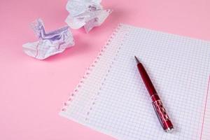 Blank paper and crumpled paper wads on pink background. Search for inspiration, writing plans. photo