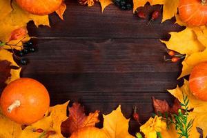 Autumn background. Frame from ripe pumpkins and fallen leaves on wooden boards. Harvest and Thanksgiving concept. photo