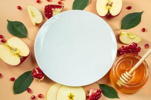 Happy Rosh Hashanah. Festive table decoration for the traditional Jewish holiday New Year. White plate and fruits with honey on yellow background. photo