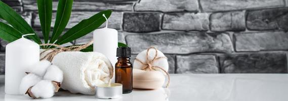 Essential oil, towel and candles on gray stone background. Spa wellness accessories and cosmetics. photo