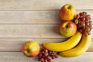 Ripe fruits on wooden background. Bananas, apples and grapes. Harvest concept. photo