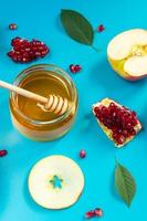 Happy Rosh Hashanah. Pattern from apples, honey and pomegranates on blue background. Jewish traditional religious holiday. photo