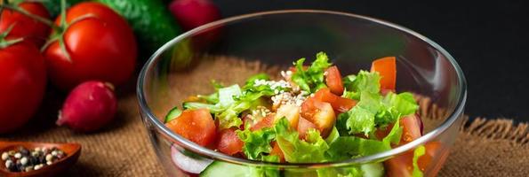 ensalada de verduras de temporada de verano en un recipiente de vidrio sobre fondo oscuro. comida orgánica vegana, comida dietética en un estilo rústico. foto