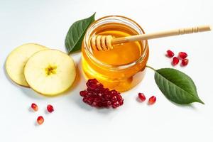 Rosh Hashanah concept. Traditional religious Jewish holiday New Year. Pomegranates, honey and apples on white background. photo