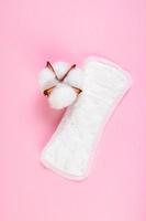 Sanitary pad and cotton flower on pink background. Daily feminine hygiene product. photo