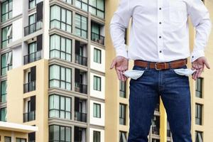 Man showing his empty pocket with blur condominium background. photo