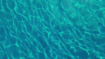 desenfoque borroso transparente color azul claro agua tranquila textura superficial con salpicaduras y burbujas. fondo de naturaleza abstracta de moda. ondas de agua a la luz del sol. cerrar el fondo del agua azul.