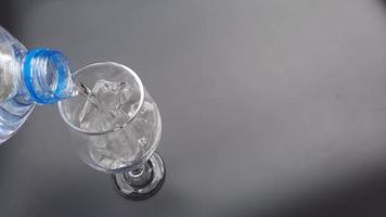 Closeup pouring water into glass with ice water at kitchen background. video