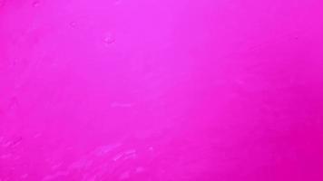 desenfoque borrosa transparente terciopelo púrpura color claro agua tranquila textura superficial con salpicaduras y burbujas. fondo de naturaleza abstracta de moda. ondas de agua con fondo de terciopelo morado. video