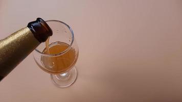 primer plano vertiendo agua de miel de abeja en un vaso sobre fondo naranja.