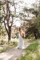 chica de novia feliz con un vestido de luz blanca con un ramo de flores secas foto