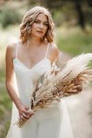 happy bride girl in a white light dress with a bouquet of dried flowers photo