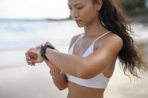 Young Beautiful woman in Bikini relaxing and using smartwatch on the beach,  Summer, vacation, holidays, and health concept. photo