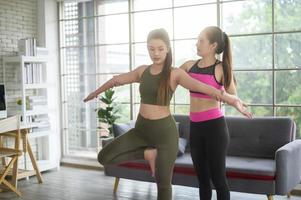 mujeres amigas jóvenes en forma haciendo yoga y meditación en casa, deporte y concepto de estilo de vida saludable. foto