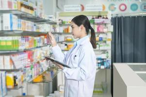 Portrait of female pharmacist using tablet in a modern pharmacy drugstore. photo