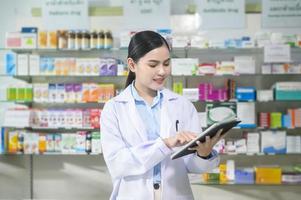 Portrait of female pharmacist using tablet in a modern pharmacy drugstore. photo