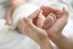 cerca de la mano que sostiene los pies del bebé recién nacido foto