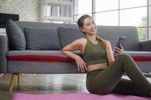 Young fitness woman in sportswear using smart phone while exercising at home, Healthy and Lifestyles. photo