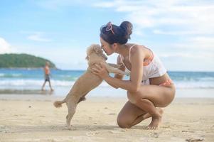 woman in Bikini with dog enjoying and relaxing on the beach,  Summer, vacation, holidays photo