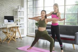 mujeres amigas jóvenes en forma haciendo yoga y meditación en casa, deporte y concepto de estilo de vida saludable. foto