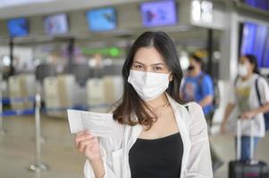 una mujer viajera lleva una máscara protectora en el aeropuerto internacional, viaja bajo la pandemia de covid-19, viajes de seguridad, protocolo de distanciamiento social, nuevo concepto de viaje normal. foto