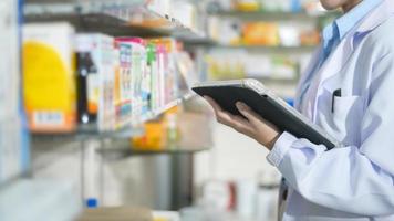 Portrait of female pharmacist using tablet in a modern pharmacy drugstore. photo